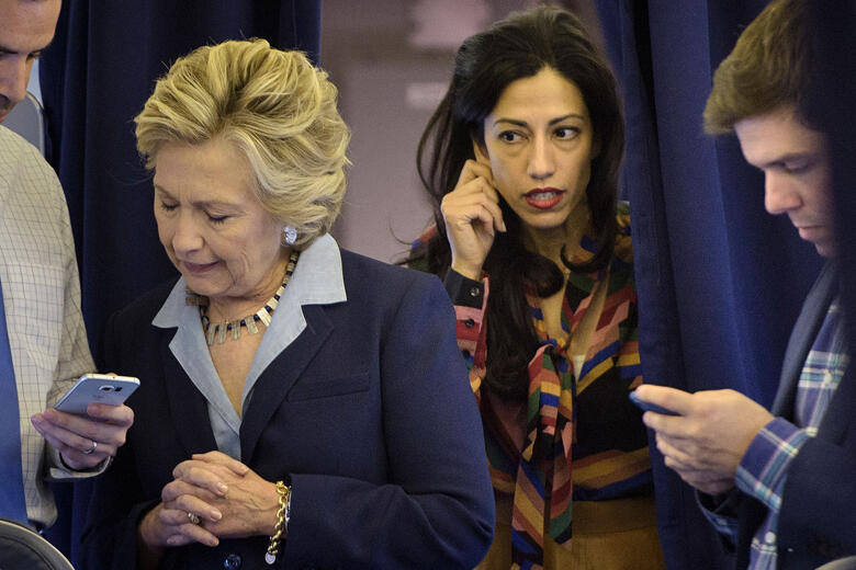 Democratic presidential nominee Hillary Clinton (2L) looks at national press secretary Brian Fallon's (L) smart phone while on her plane with aid Huma Abedin (2R) and traveling press secretary Nick Merrill (R) at Westchester County Airport October 3, 2016