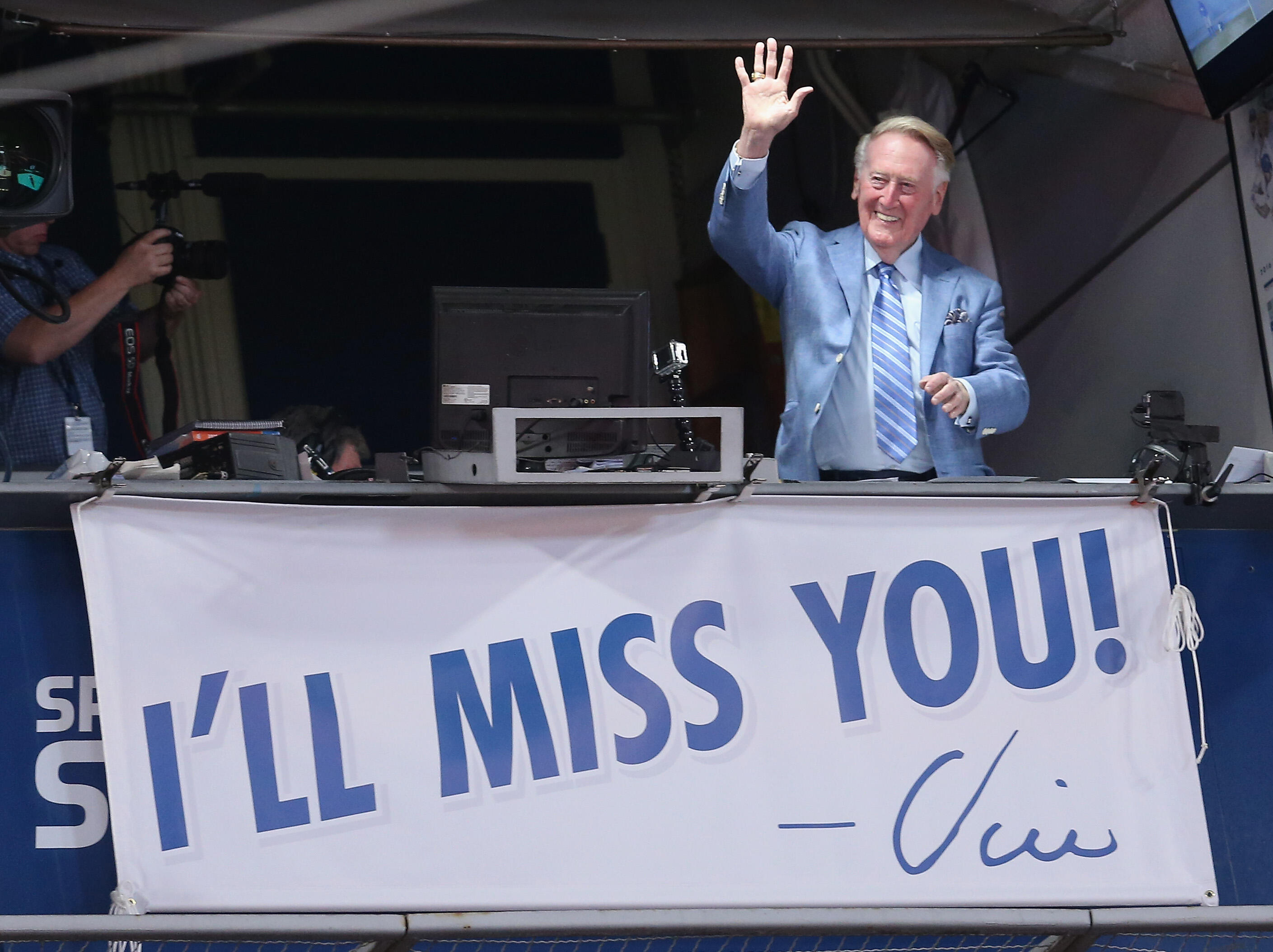 LOS ANGELES, CALIFORNIA - SEPTEMBER 24:  Los Angeles Dodgers broadcaster Vin Scully waves to the crowd after leading in the singing of Take Me Out to the Ball Game during the seventh inning stretch of the game with the Colorado Rockies at Dodger Stadium o