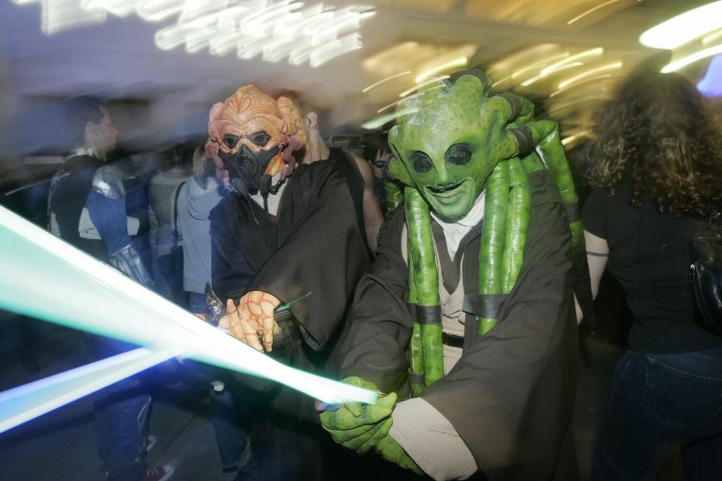 Two people in costume play with light sw