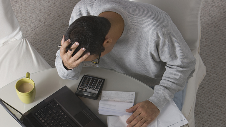 Overhead view of frustrated Hispanic man paying bills