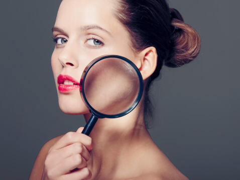 Woman holding magnifying glass to face