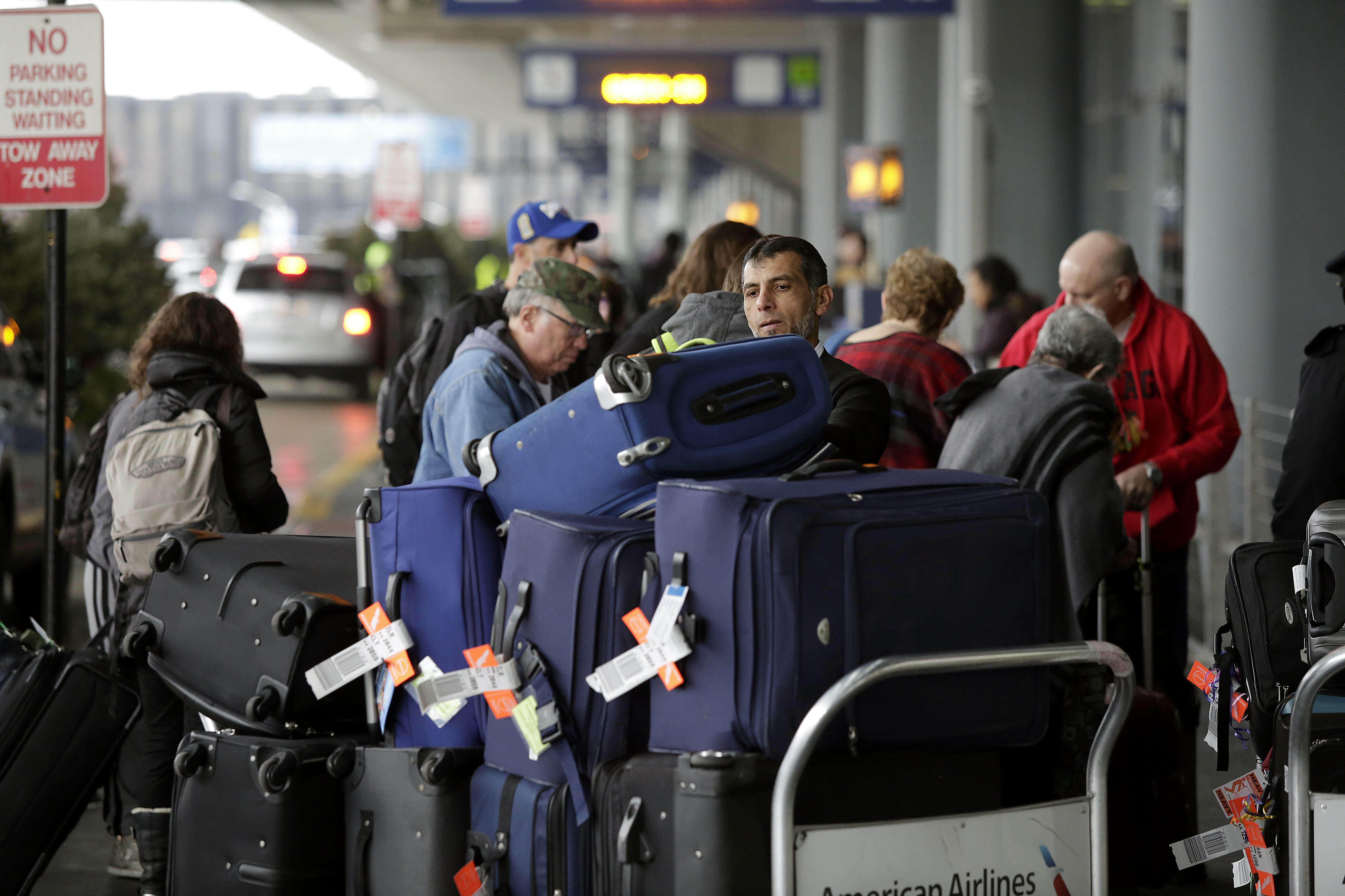 CHICAGO, IL - DECEMBER 23 : An airport worker organizes luggage on a cart as travelers in the back ground and in the pre check-in line at O'Hare International Airport on December 23, 2016 in Chicago, Illinois. O'hare International Airport is one of the bu