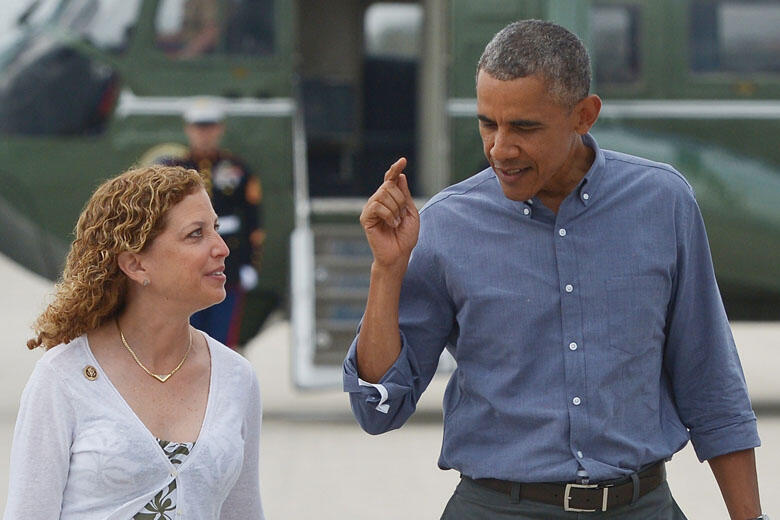 US President Barack Obama chats with DNC chair Debbie Wasserman Schultz as he makes his way to Air Force One shortly before departing from Miami International Airport in Miami on April 22, 2015. AFP PHOTO/ MANDEL NGAN        (Photo credit should read MAND