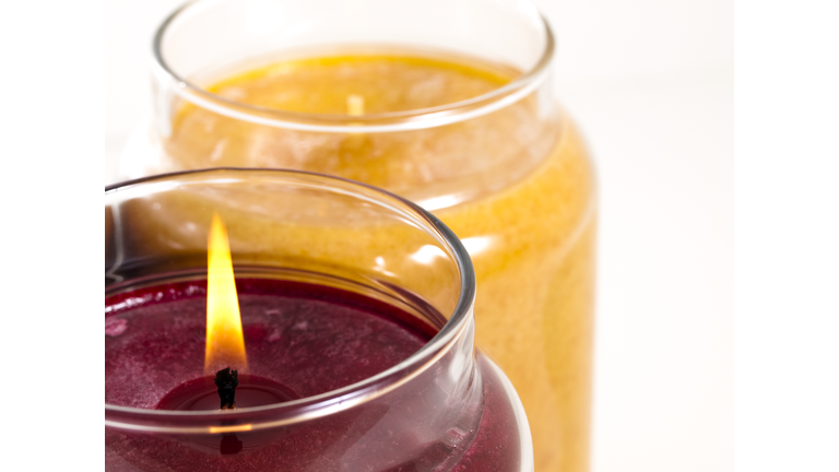A maroon candle burning next to an orange candle not burning