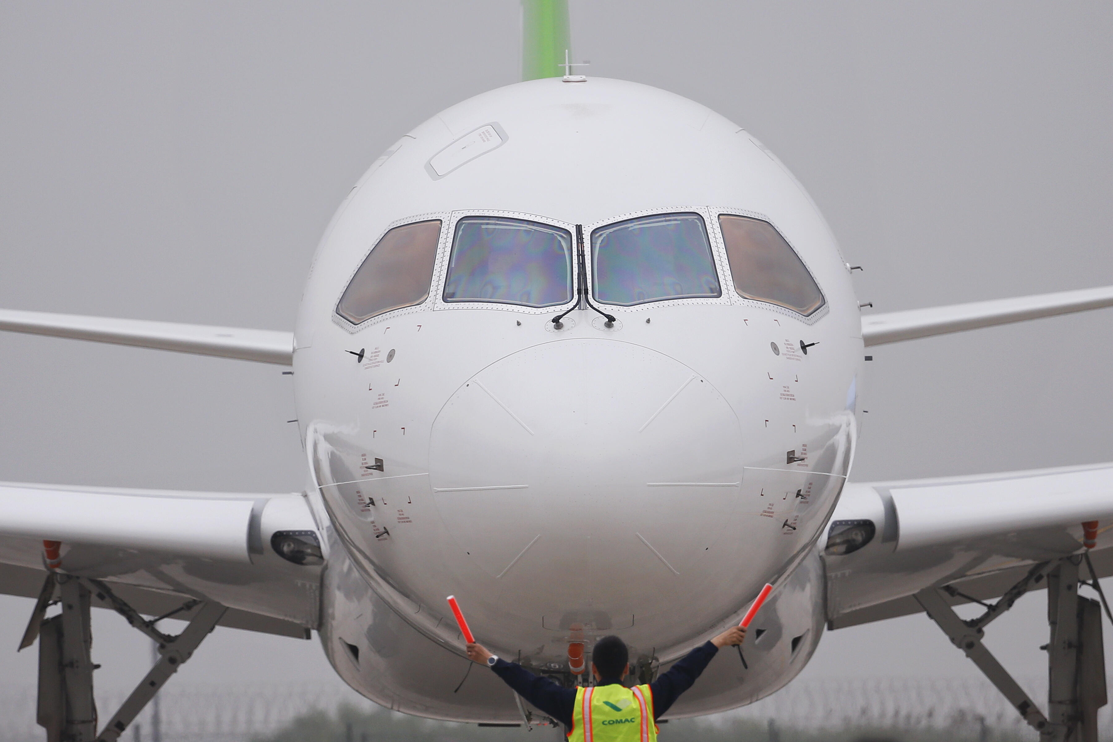 A member of staff signals in front of China's home-grown C919 passenger jet after it landed on its maiden flight at Pudong International Airport in Shanghai on May 5, 2017. The first large made-in-China passenger plane took off on its maiden test flight o