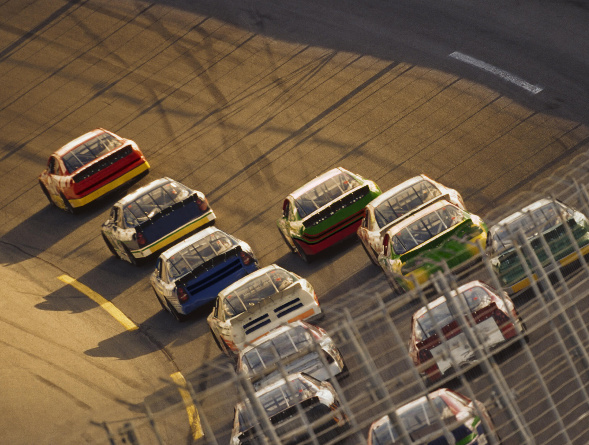 Stock car race, safety fence in foreground, elevated view