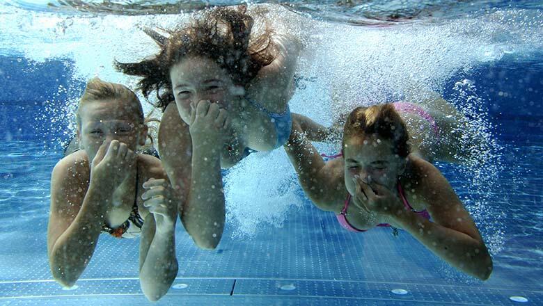 Three girls dive in a swimming pool on A