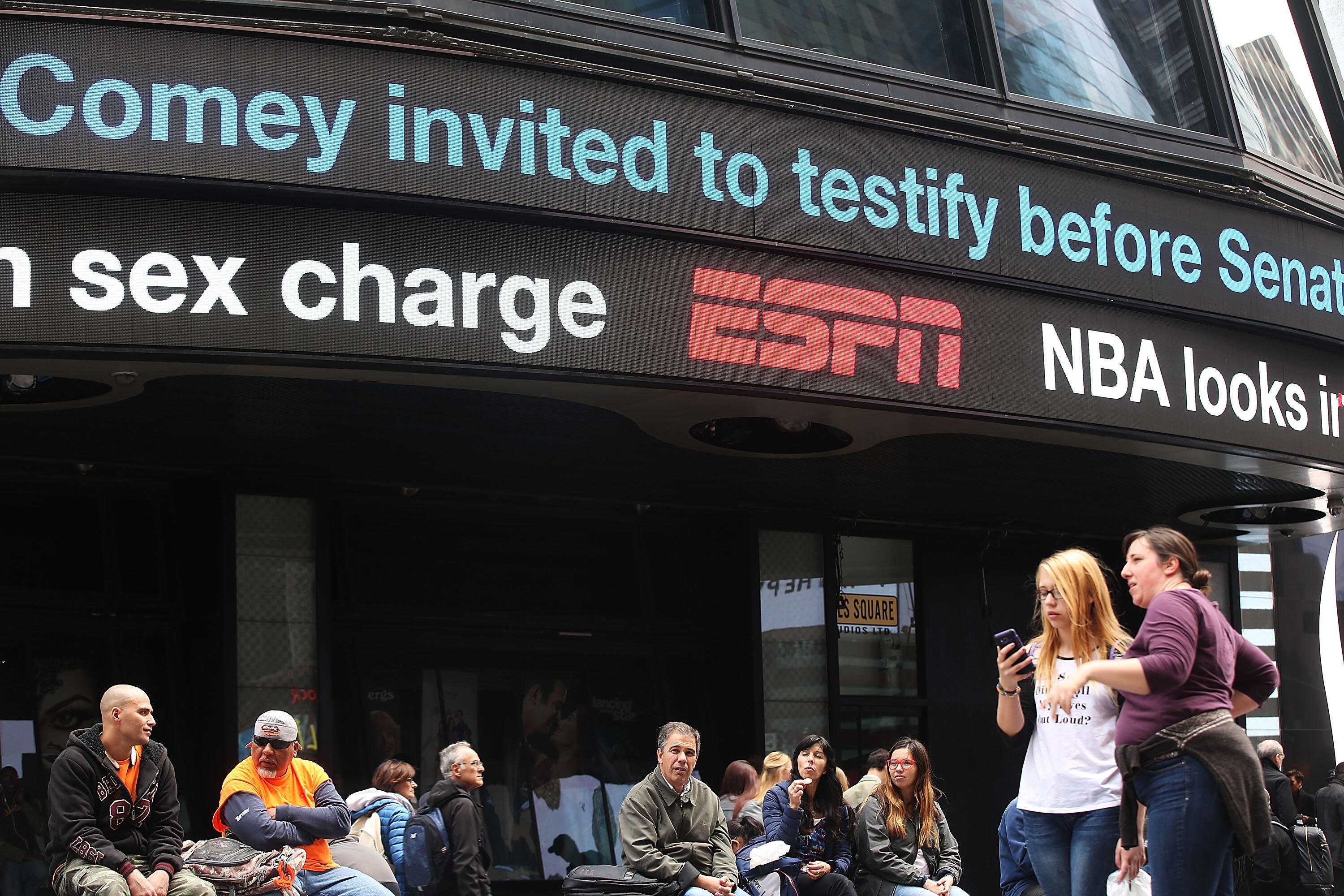 NEW YORK, NY - MAY 10: People congregate in Times Square under news about former FBI Director James Comey on May 10, 2017 in New York City. Comey was fired by President Trump yesterday, only days after he requested more resources from the Justice Departme