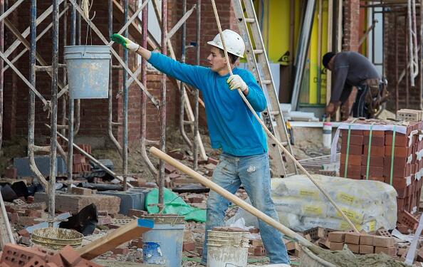 A brick mason assistant lifts heavy buckets of cement to the crew covering a new home in bricks in Ashburn, Virginia on January 2, 2015.  US spending on construction fell slightly in November from the previous month driven by a decline in non-residential building, but was higher from a year ago, the Commerce Department reported Friday. AFP Photo/PAUL J. RICHARDS        (Photo credit should read PAUL J. RICHARDS/AFP/Getty Images)