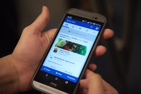 A man check his facebook on his smart phone with a message reading 