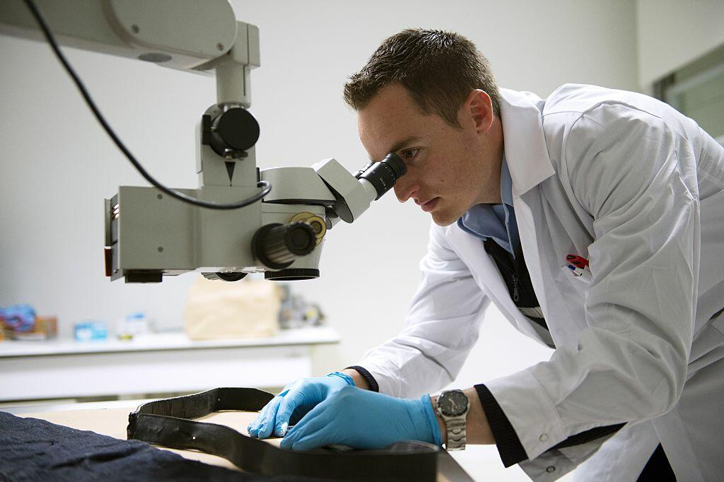 A forensic scientist of the Criminal Research Institute of the National Gendarmerie (IRCGN), looks through a microscope, on May 19, 2015 in Pontoise, outside Paris. A scanner for autopsies, a collection of 8,000 weapons, 