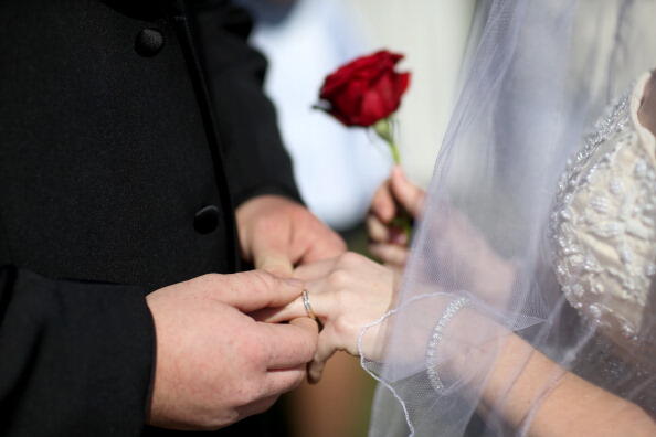 WEST PALM BEACH, FL - FEBRUARY 14: A couple exchanges rings as they are wed during a group Valentine's day wedding at the National Croquet Center on February 14, 2014 in West Palm Beach, Florida. Approximately 40 couples were married in a ceremony put on 