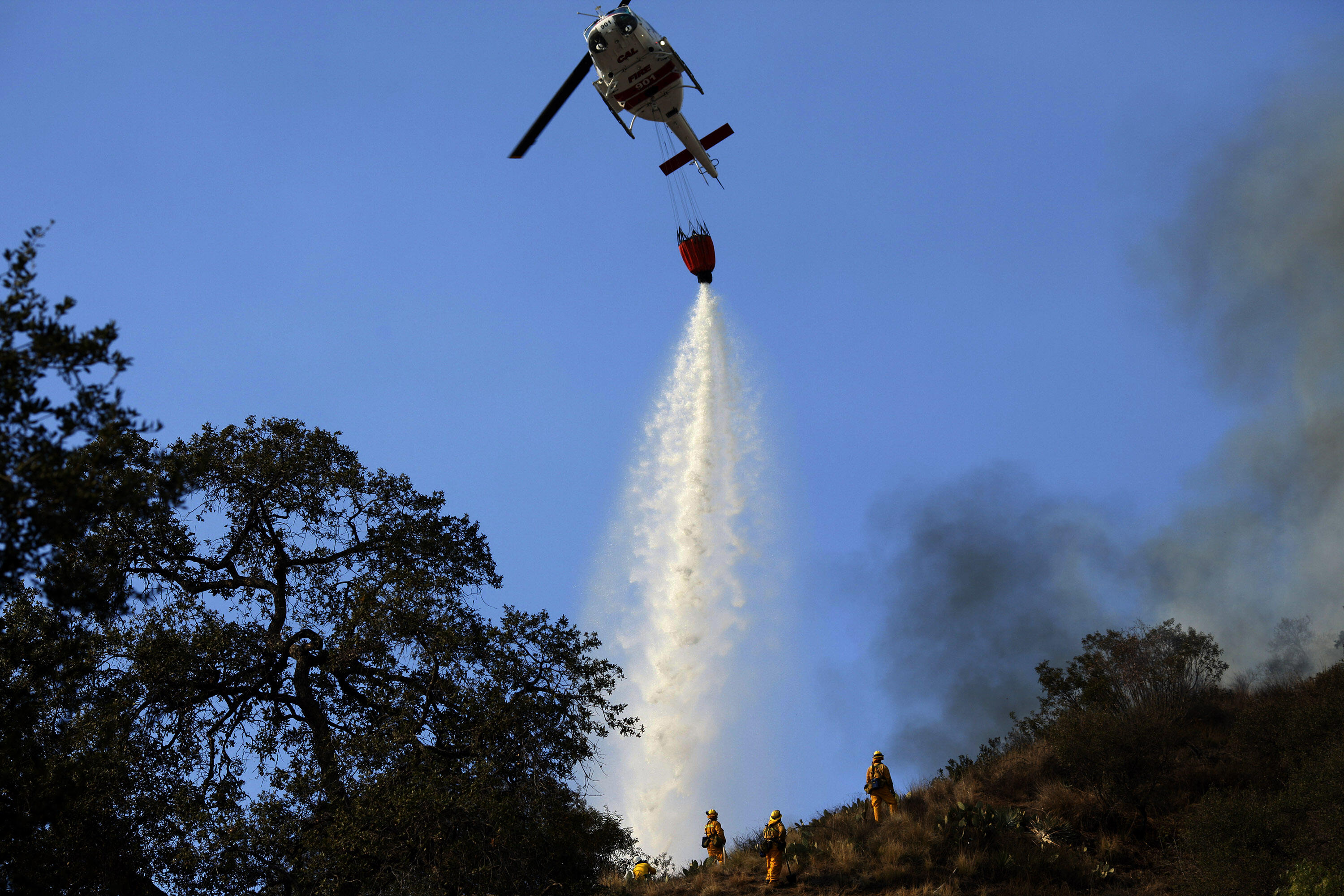 GLENDORA, CA - JANUARY 16: Helicopters drop water on the wildfires as they burn through the hillsides on January 16, 2014 in Glendora, California. A wildfire near Glendora in the San Gabriel Valley has prompted officials to order evacuations for houses ne
