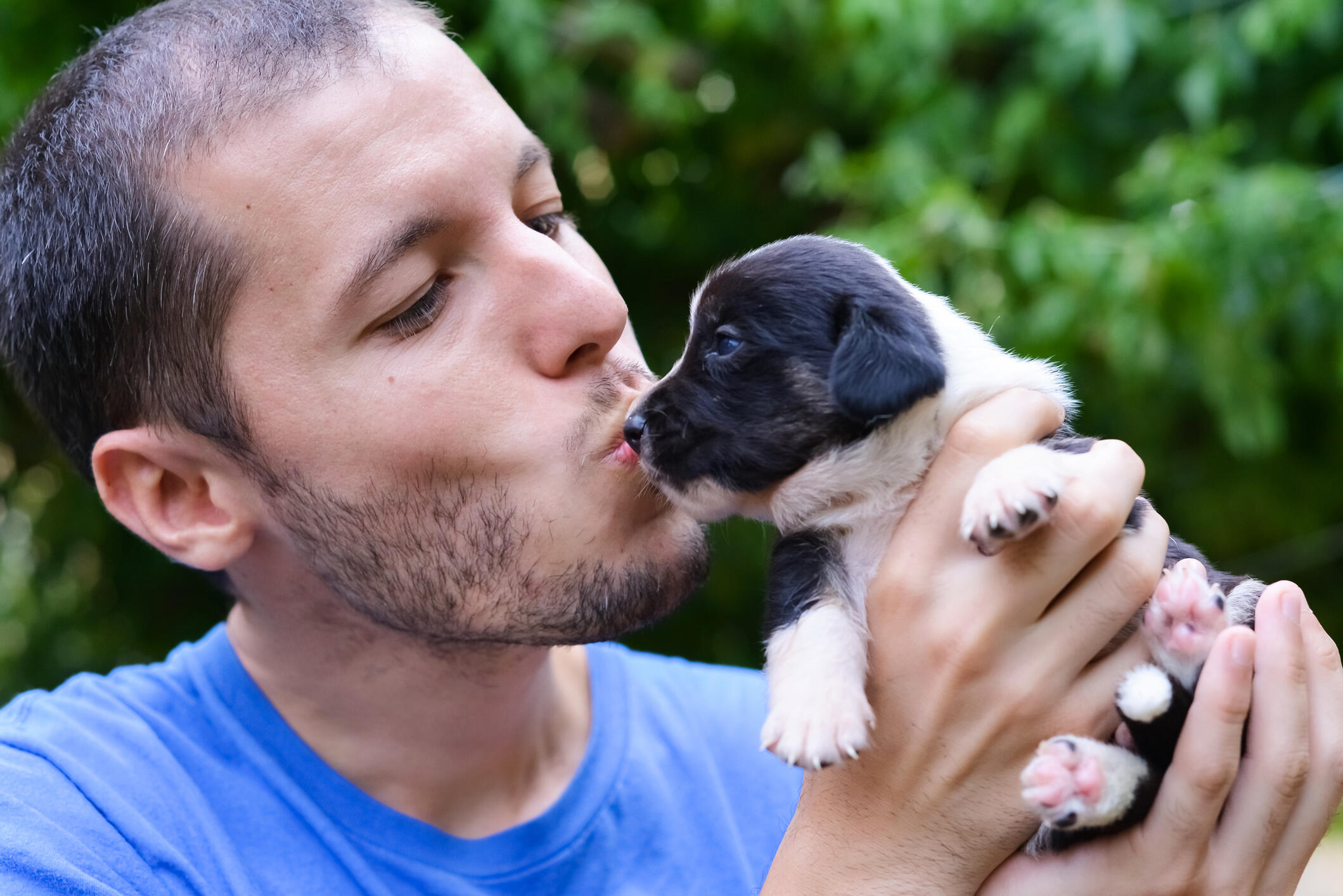 Boy holding carefully a small puppy with hands.Owner w/ emotional attitude toward his dog.