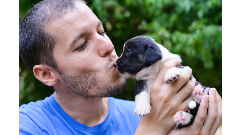 Man w/ beard kissing the face of a cute puppy