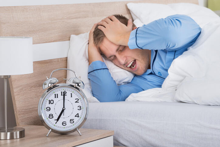Sleeping Man Disturbed By Ringing Alarm Clock After A Sleepless Night