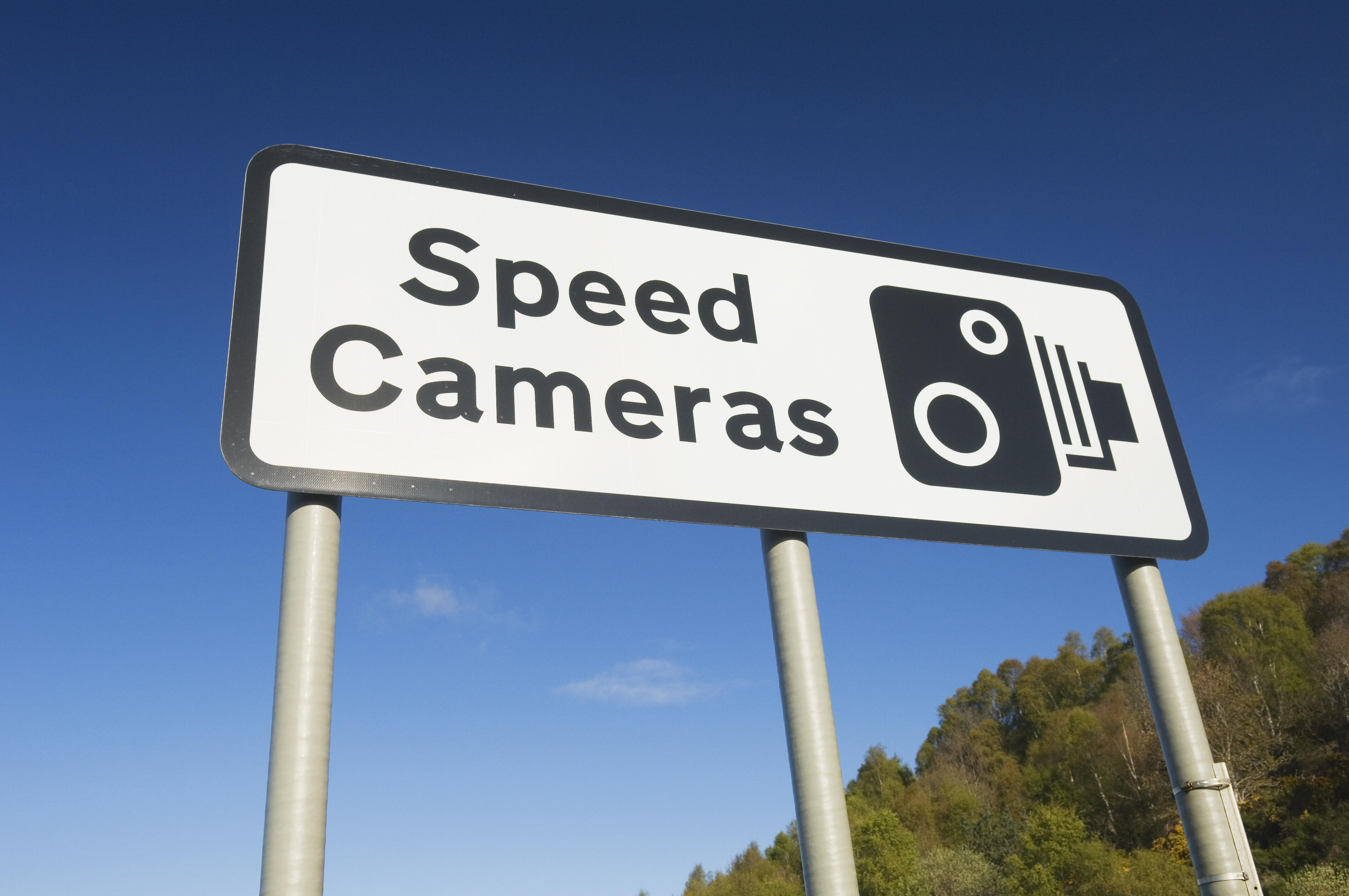 Speed cameras sign against a clear blue sky.