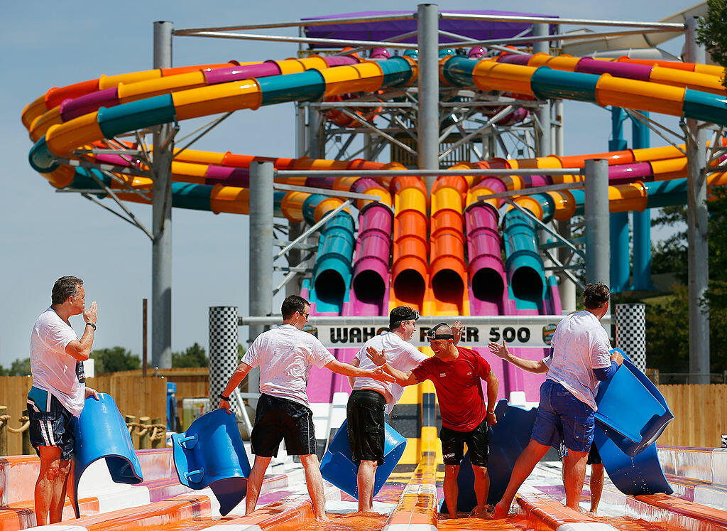 ARLINGTON, TX - MAY 20:  (2nd from R) IndyCar driver and defending Indy 500 champion Tony Kanaan reacts after riding on the new Wahoo Racer water slide with a group of local dignitaries at Hurricane Harbor on May 20, 2014 in Arlington, Texas.  (Photo by T