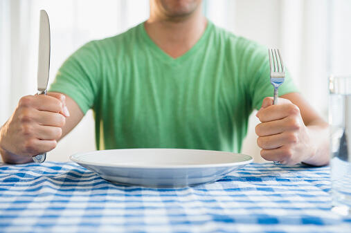 Mixed race man holding fork and knife at table