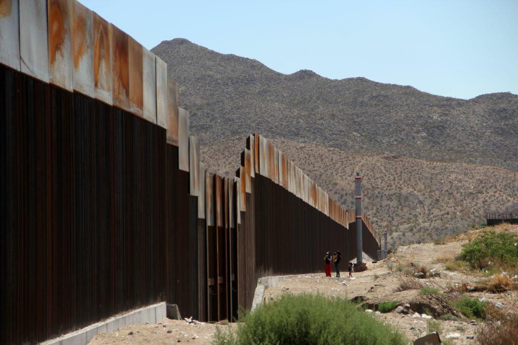 TOPSHOT - A Mexican family stands next to the border wall between Mexico and the United States, in Ciudad Juarez, Mexico on May 23, 2017.  The United States is about to complete the construction of a metal wall nearly seven meters high on the border between Ciudad Juarez and El Paso, Texas, replacing a wire mesh fence dating back to 1986, officials said. / AFP PHOTO / HERIKA MARTINEZ        (Photo credit should read HERIKA MARTINEZ/AFP/Getty Images)