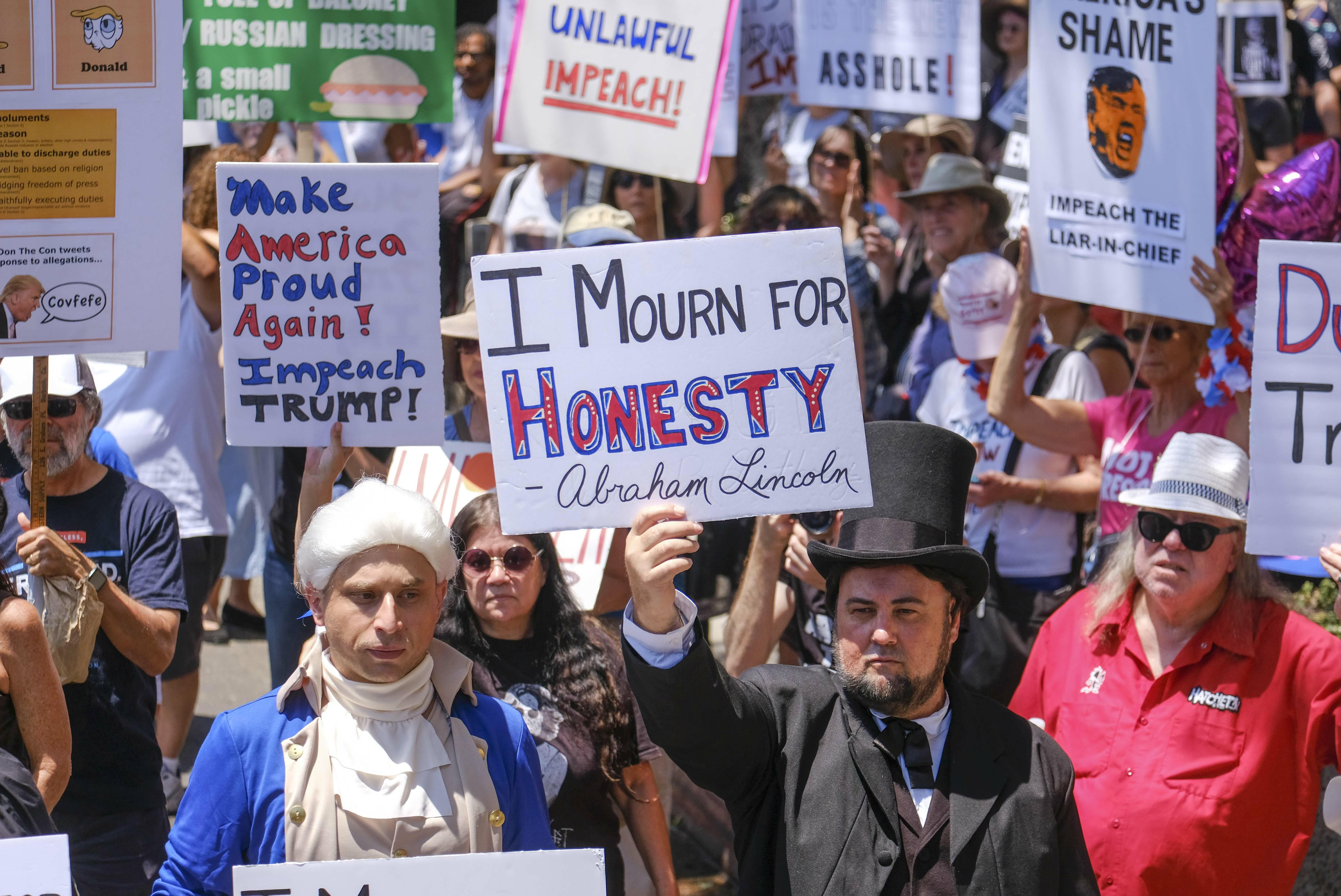 Demonstrators carry signs during the Impeachment March to call for Congress to start impeachment hearings against US President Donald Trump,  in Los Angeles, California, on July 2, 2017.  / AFP PHOTO / RINGO CHIU        (Photo credit should read RINGO CHI