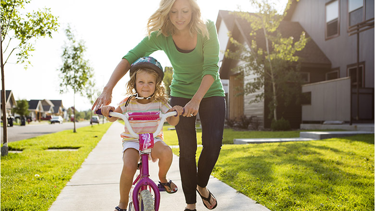Young girl learning to ride a bike.