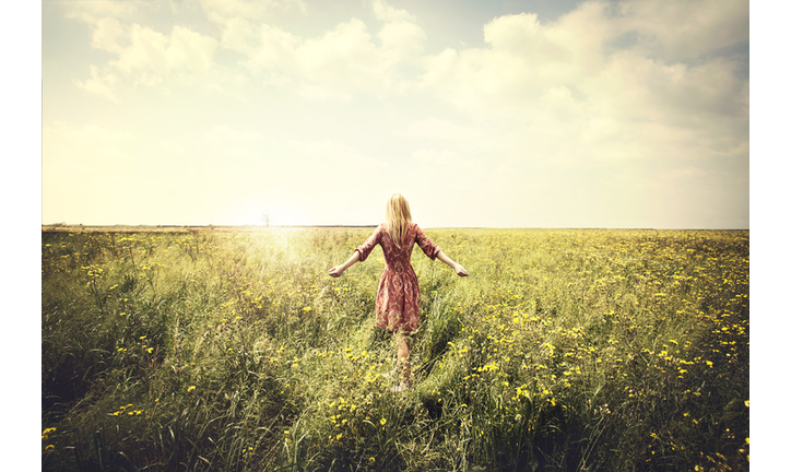 dreamy woman walking in nature towards the sun