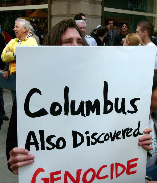 NEW YORK - OCTOBER 11: A man holds up an anti-Columbus sign during the Columbus Day Parade October 11, 2004, in New York City. The parade, which celebrates Italian heritage and Christopher Columbus' landing in America, featured historic race cars and sports cars. (Photo by Spencer Platt/Getty Images)