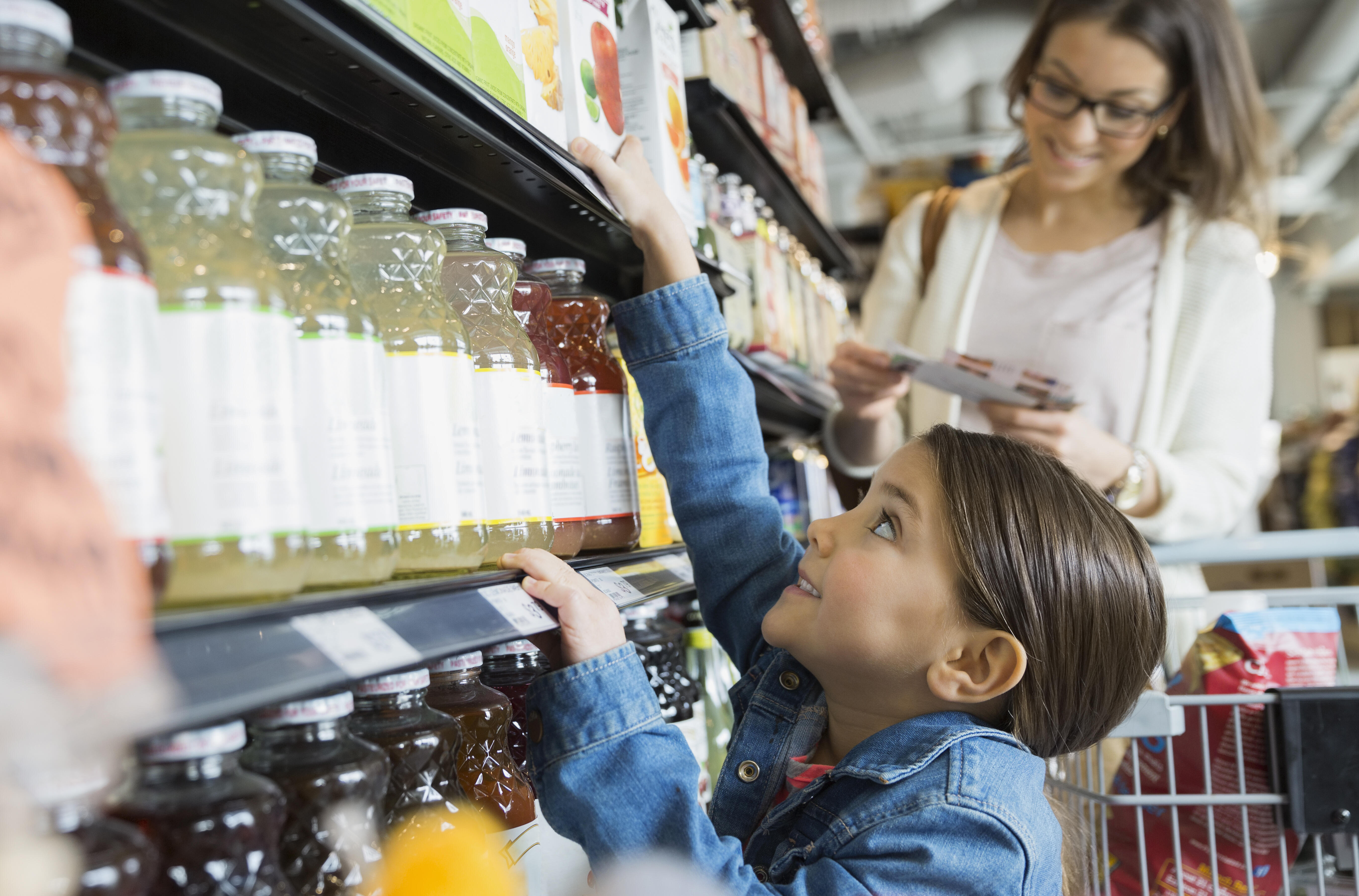 A child reaches for juice at a supermarket.