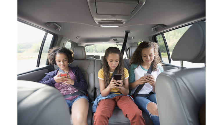 Kids in a car looking at screens