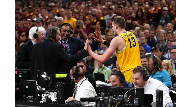 Moritz Wagner #13 of the Michigan Wolverines high fives TV personalities Jim Nantz, Bill Raftery and Grant Hill 