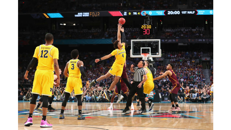 Isaiah Livers #4 of the Michigan Wolverines and Cameron Krutwig #25 of the Loyola Ramblers go up for the opening tip 