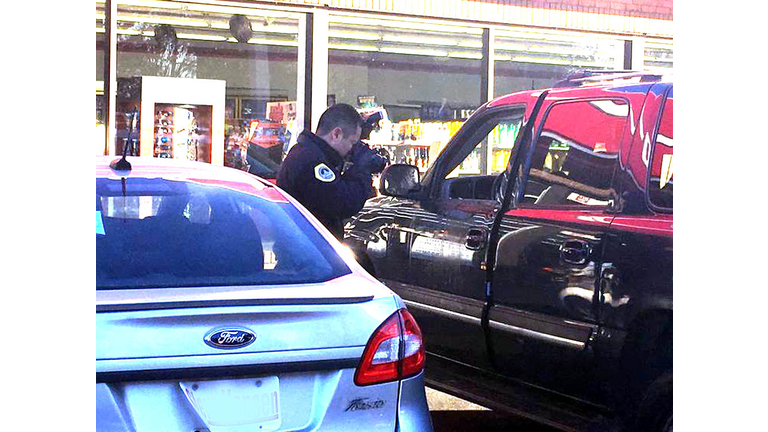 Detective photographs bullet holes in car after rolling shooting near Lincoln High School November 30, 2017. Photo Wendy Wilde