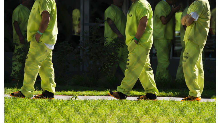 Men wearing neon-colored jail clothes signifying immigration detainees walk to pick up their lunches at the Theo Lacy Facility, a county jail which houses convicted criminals as well as immigration detainees, March 14, 2017 in Orange, California
