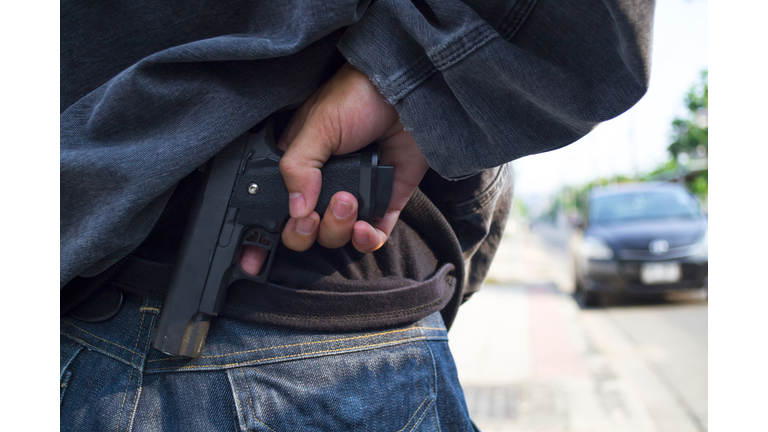 Robber holding a gun at abandoned building. Low key photo and selective focus. criminality concept. (Credit: 	seksan Mongkhonkhamsao/Royalty -Free/ Getty Images)