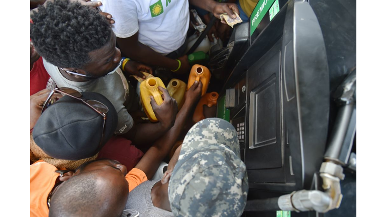 Haitian people wait to purchase fuel at a gas station in the commune of Petion Ville in the Haitian capital Port-au-Prince, July 9, 2018, one of the few gas stations open during the strike to protest the hike in fuel prices. - Scenes of anarchy alternate with tentative indications of a return to normalcy in Haiti's capital after two days of deadly looting and arson triggered by a quickly-aborted government attempt to raise fuel prices. (Photo by HECTOR RETAMAL / AFP)