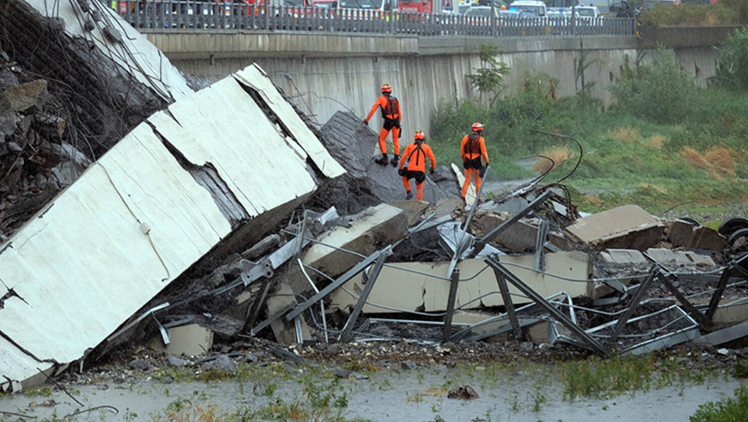 Rescuers are at work, on August 14, 2018 in Genoa, at a section of a giant motorway bridge that collapsed earlier injuring several people
