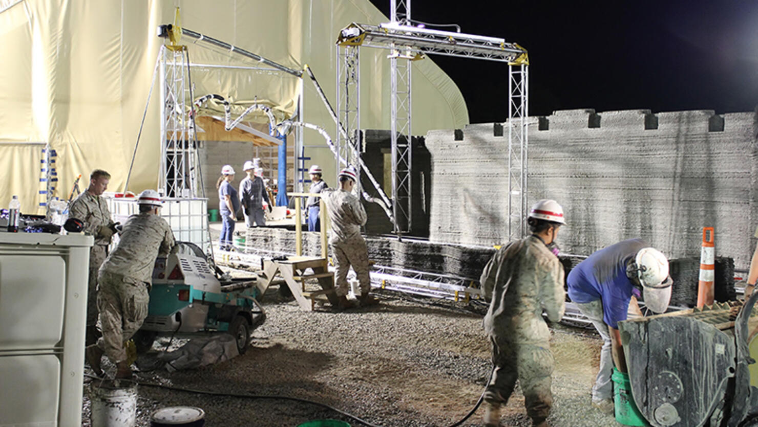 Marines from I Marine Expeditionary Force learn how to operate the world's largest concrete 3D printer as it constructs a 500-square-foot barracks hut at the U.S. Army Engineer Research and Development Center in Champaign, Illinois. 