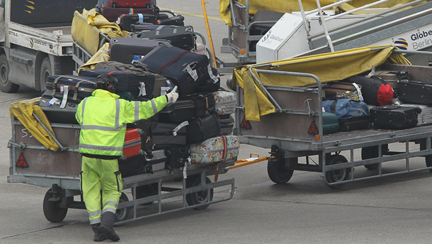 A baggage handler loads luggage onto an airplane