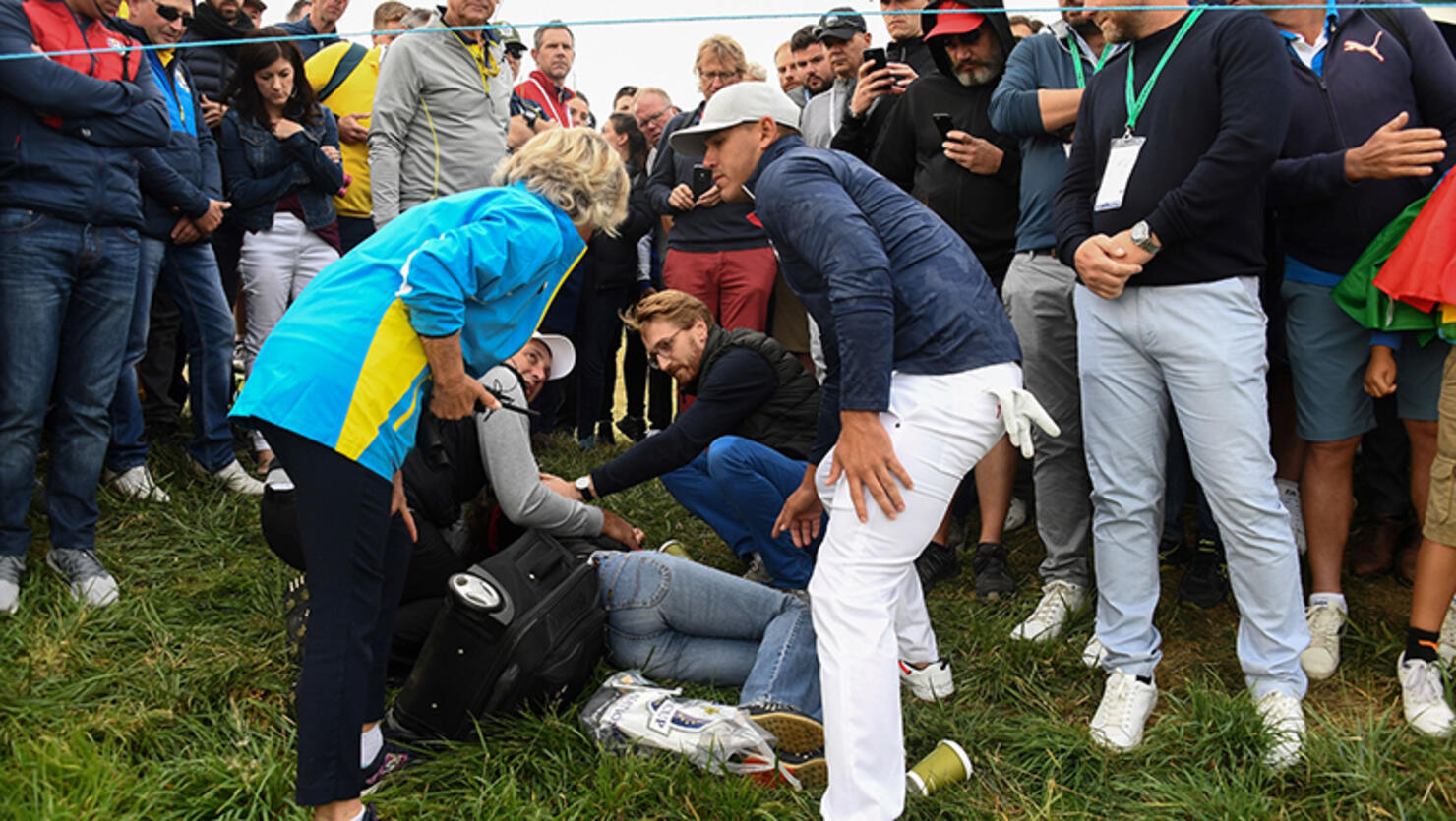 US golfer Brooks Koepka (R) reacts next to an injured spectator who fell during the fourball match on the first day of the 42nd Ryder Cup at Le Golf National Course at Saint-Quentin-en-Yvelines