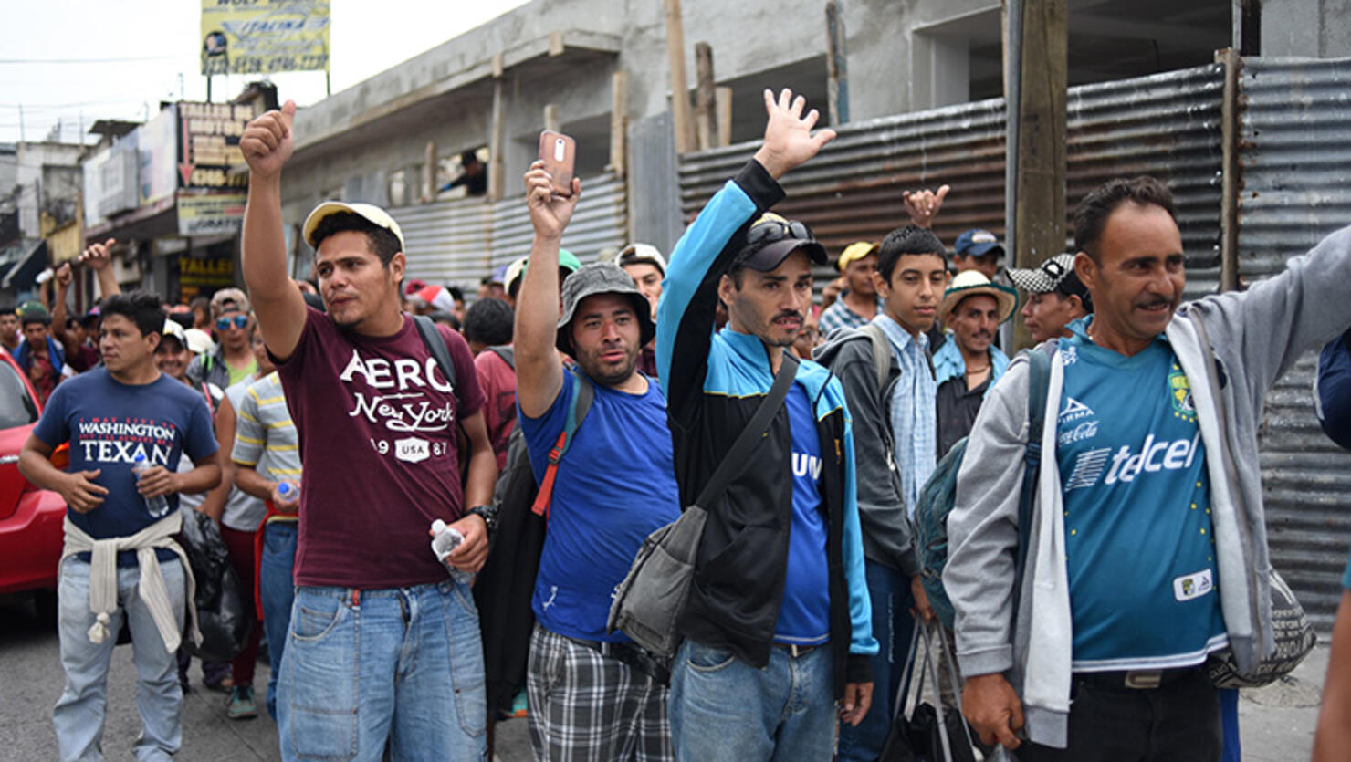 Honduran migrants heading to the United States hold up their hands as they arrive at the Casa del Migrante (Migrant's House) in Guatemala City