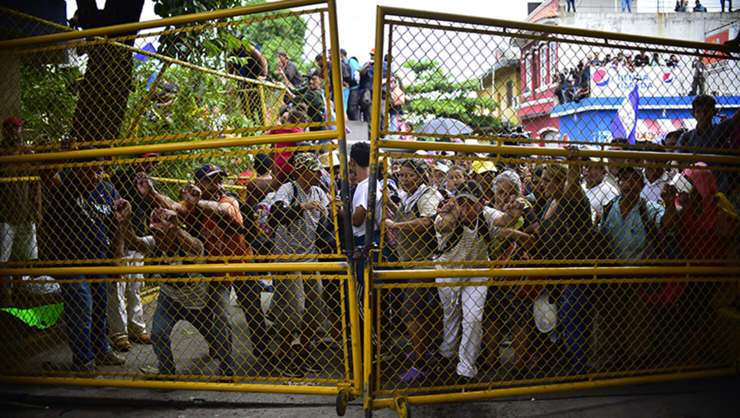 Honduran migrants heading in a caravan to the US push to tear down the gate of the Guatemala-Mexico international border bridge in Ciudad Hidalgo, Chiapas state, Mexico