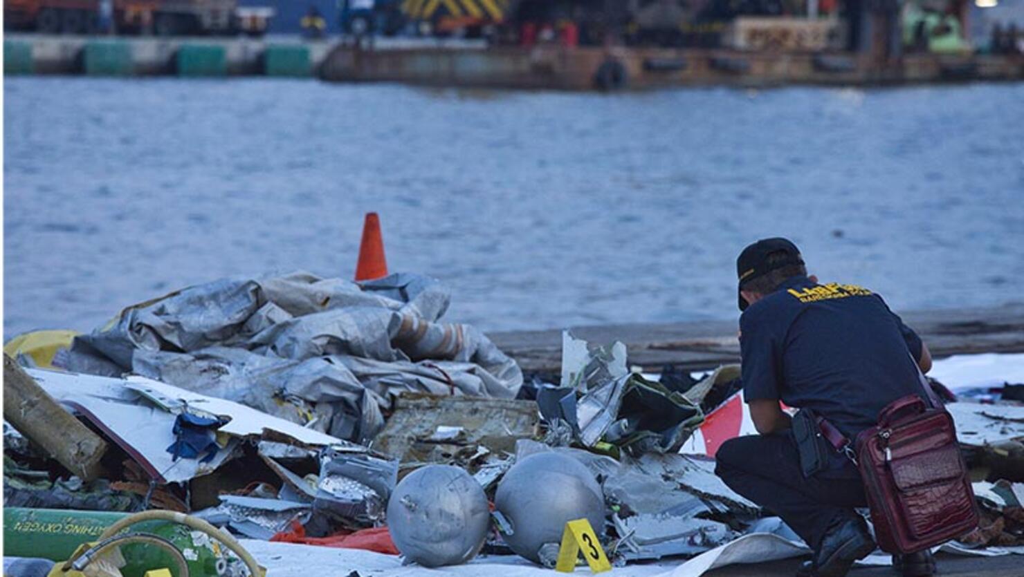 A forensic investigator looks through the remains of Lion Air flight JT 610 at the Tanjung Priok port on October 29, 2018 in Jakarta, Indonesia.