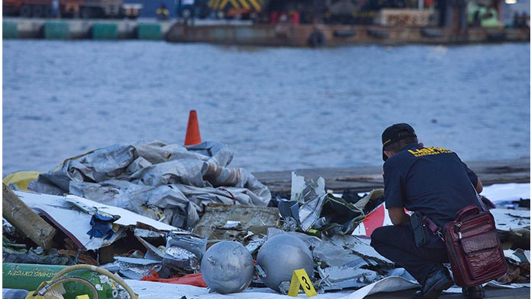 A forensic investigator looks through the remains of Lion Air flight JT 610 at the Tanjung Priok port on October 29, 2018 in Jakarta, Indonesia.