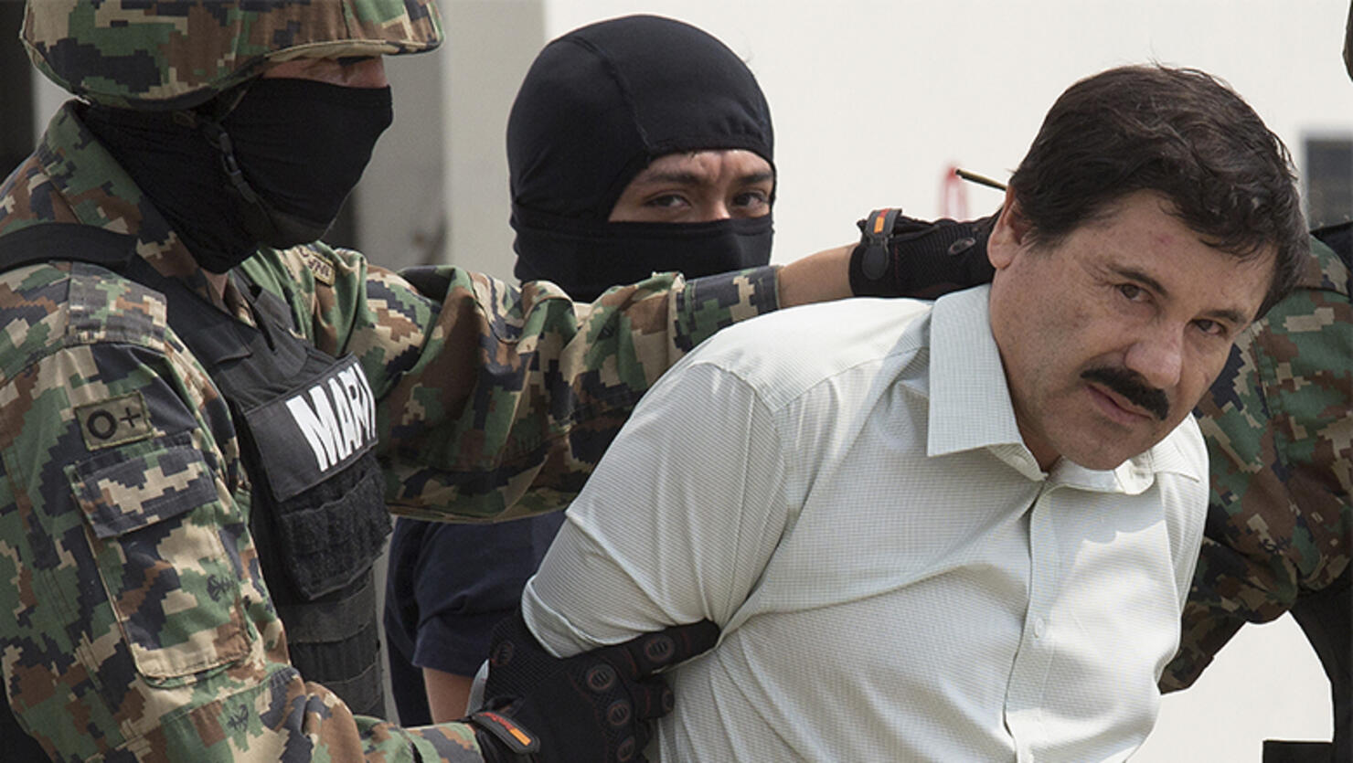 Drug trafficker Joaquin 'El Chapo' Guzman is escorted to a helicopter by Mexican security forces 
