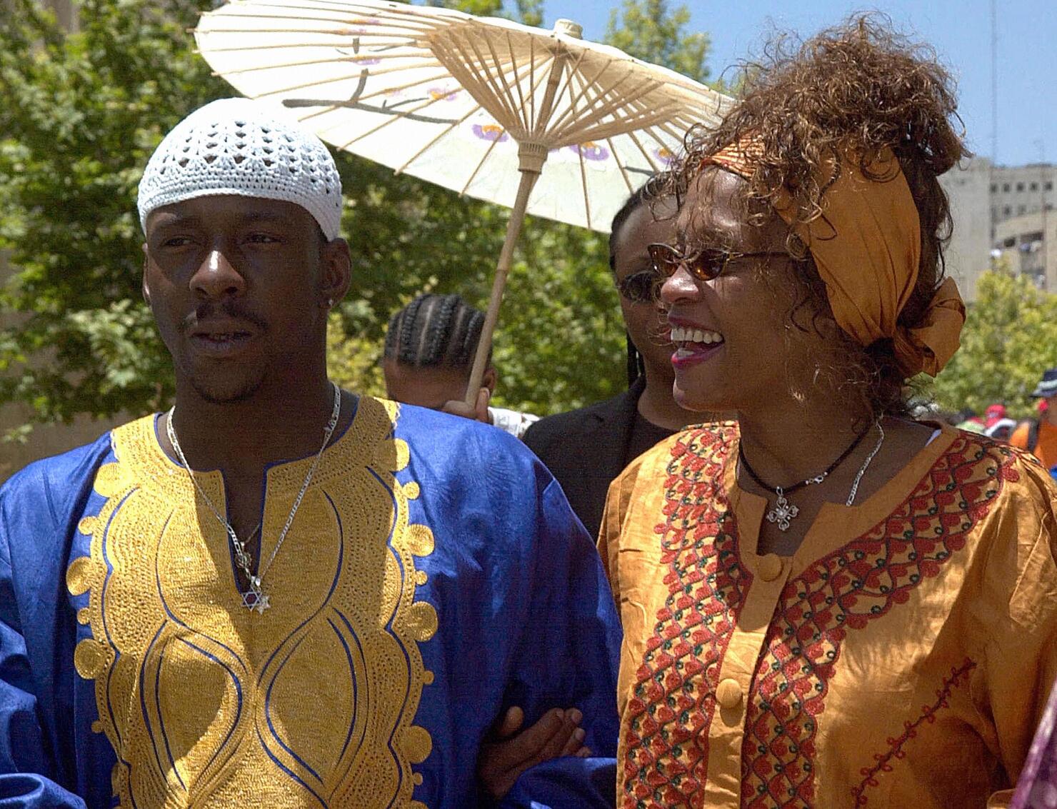 FILES-MIDEAST-ISRAEL-WHITNEY HOUSTON (FILES)US singer and actress Whitney Houston(R) smiles as she walks with her husband Bobby Brown next to the 'Wailing Wall' or Western Wall in the old city of Jerusalem 28 May 2003. The rocky marriage of Houston, whose popular tunes include 'Love is a Contact Sport,' has suffered another jolt after her husband, singer Bobby Brown. Brown was formally charged 10 December 2003 with beating her in the couple's home in a Atlanta suburb. Fulton County police spokesman Kurtis Young said the altercation inside the mansion near Alpharetta, Georgia, had forced the world-famous diva to plead for help in a frantic emergency call to police. The reason for the argument was not mentioned, but the marriage of 13 years has had a number of rough patches before. AFP PHOTO/STR / AFP PHOTO (Photo credit should read /AFP/Getty Images)