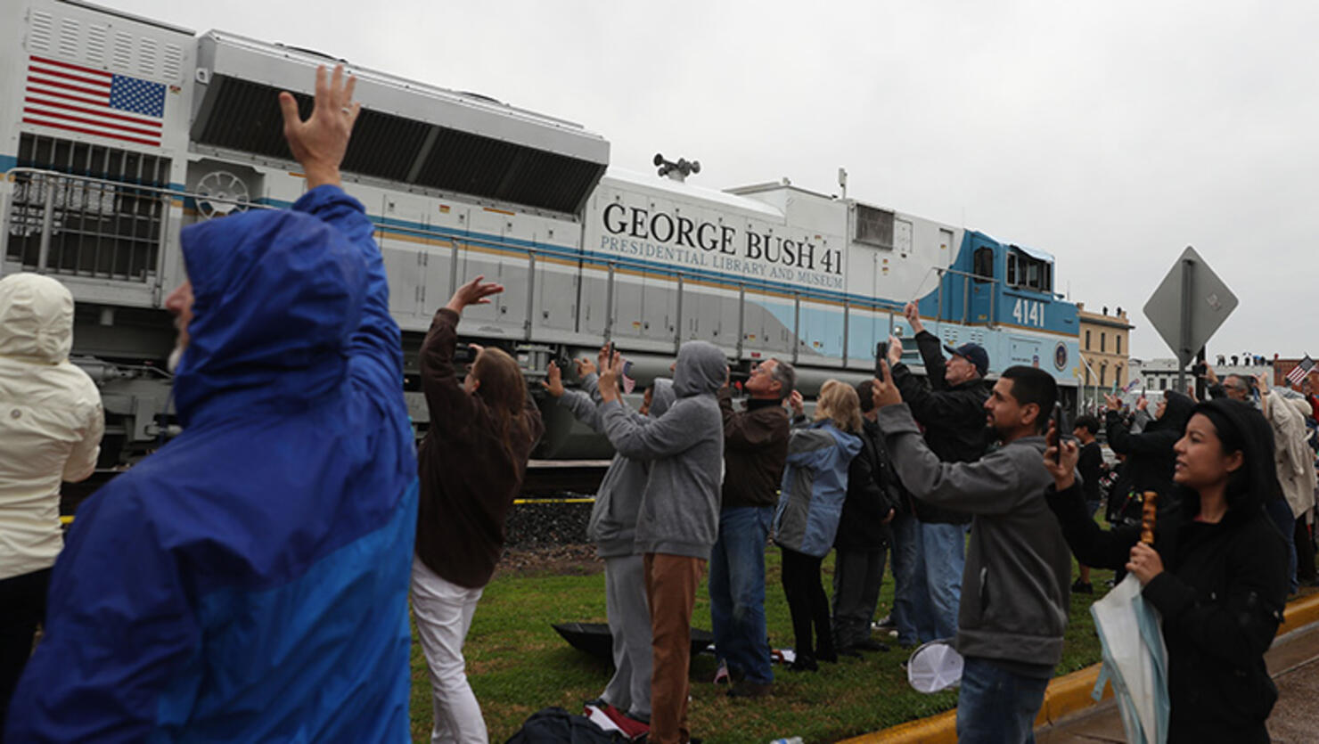 People wave at the train carrying the casket of former U.S. President George H.W. Bush to the George H.W. Bush Presidential Library at Texas A&M University