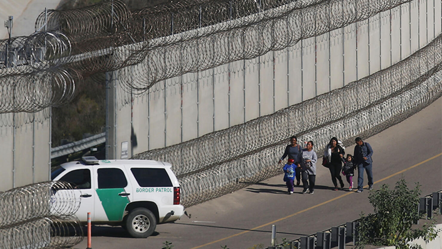 Migrants walk while being taken into custody by the U.S. Border Patrol after crossing the U.S.-Mexico border fence and turning themselves in