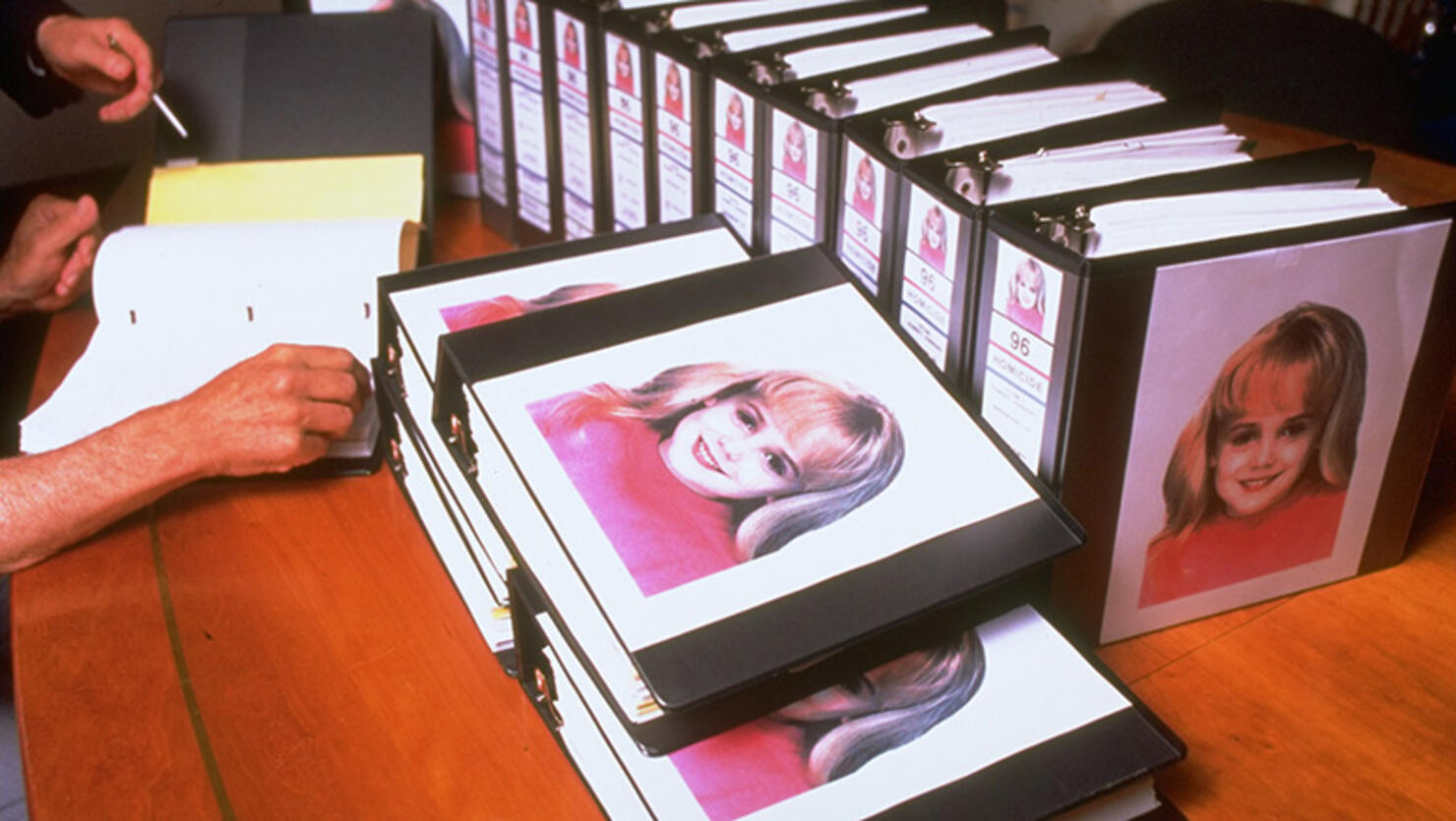 Murdered 6-yr-old beauty queen JonBenet Ramsey's image amblazoned on dozens of binders crammed w. investigators's reports for case which still unsolved