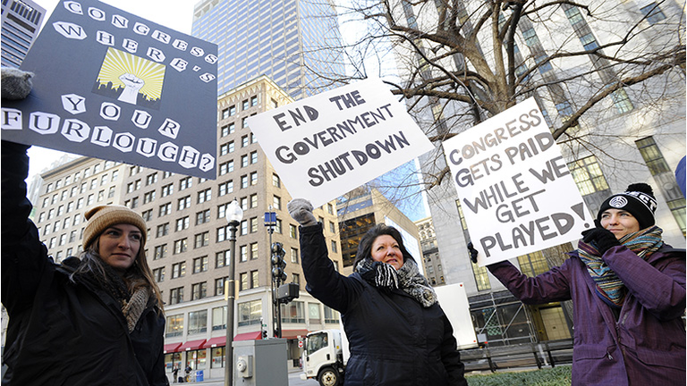 EPA employee Rosanne Sawaya-Obrien (C) holds her sign calling for an end to the government shutdown during a rally and protest by government workers and concerned citizens at Post Office Square near the Federal building, headquarters for the EPA and IRS in Boston